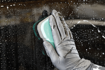 濡れた車のボディに専用スポンジを当てて鉄粉を除去している手元のクローズアップ