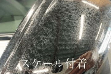 自動車のピラー部分に白くウロコ状に固着したスケール汚れが目立つ様子(テキスト「スケール付着」入り)